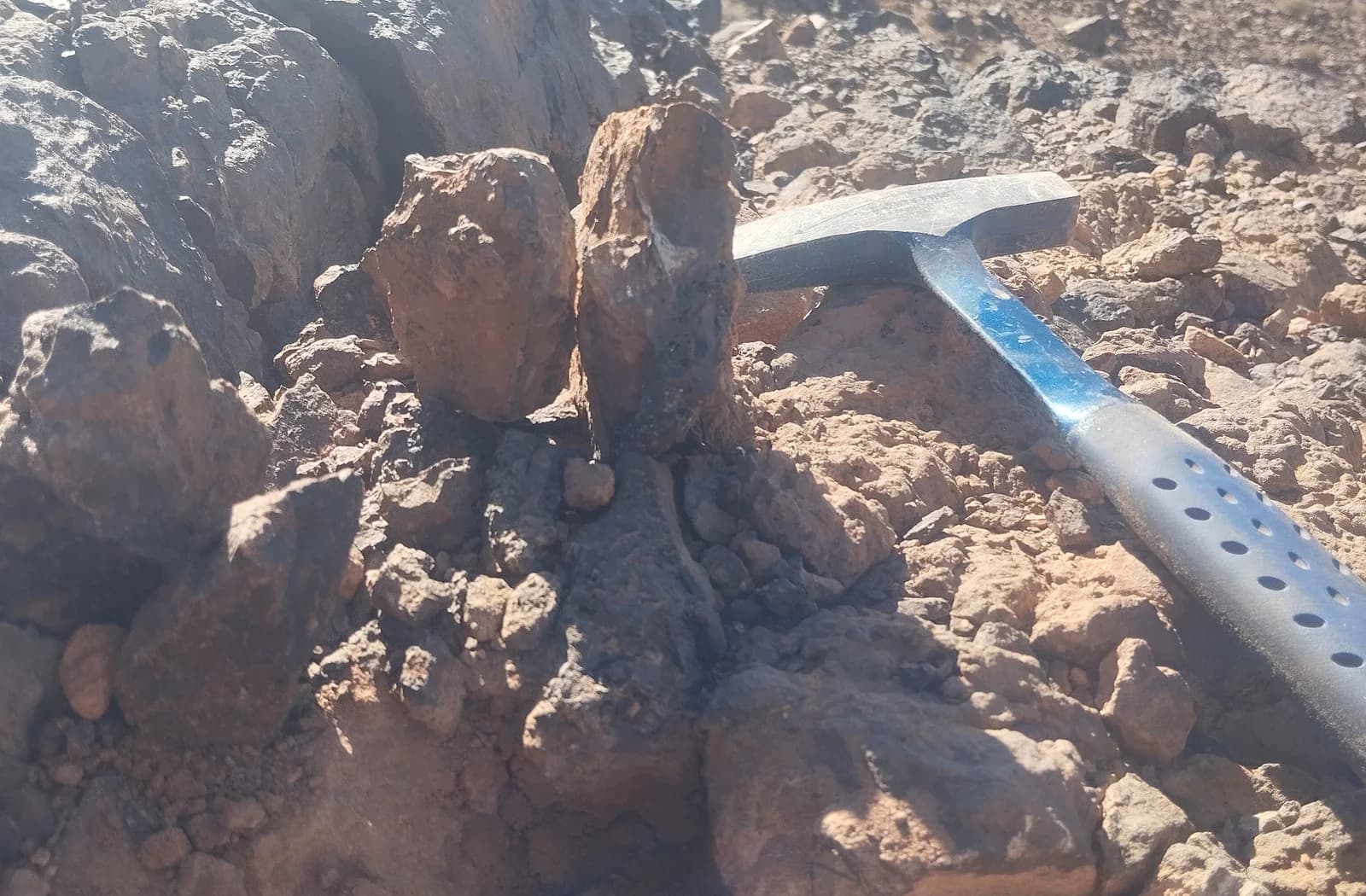 Géologue examinant des blocs rocheux à l’aide d’un marteau de terrain