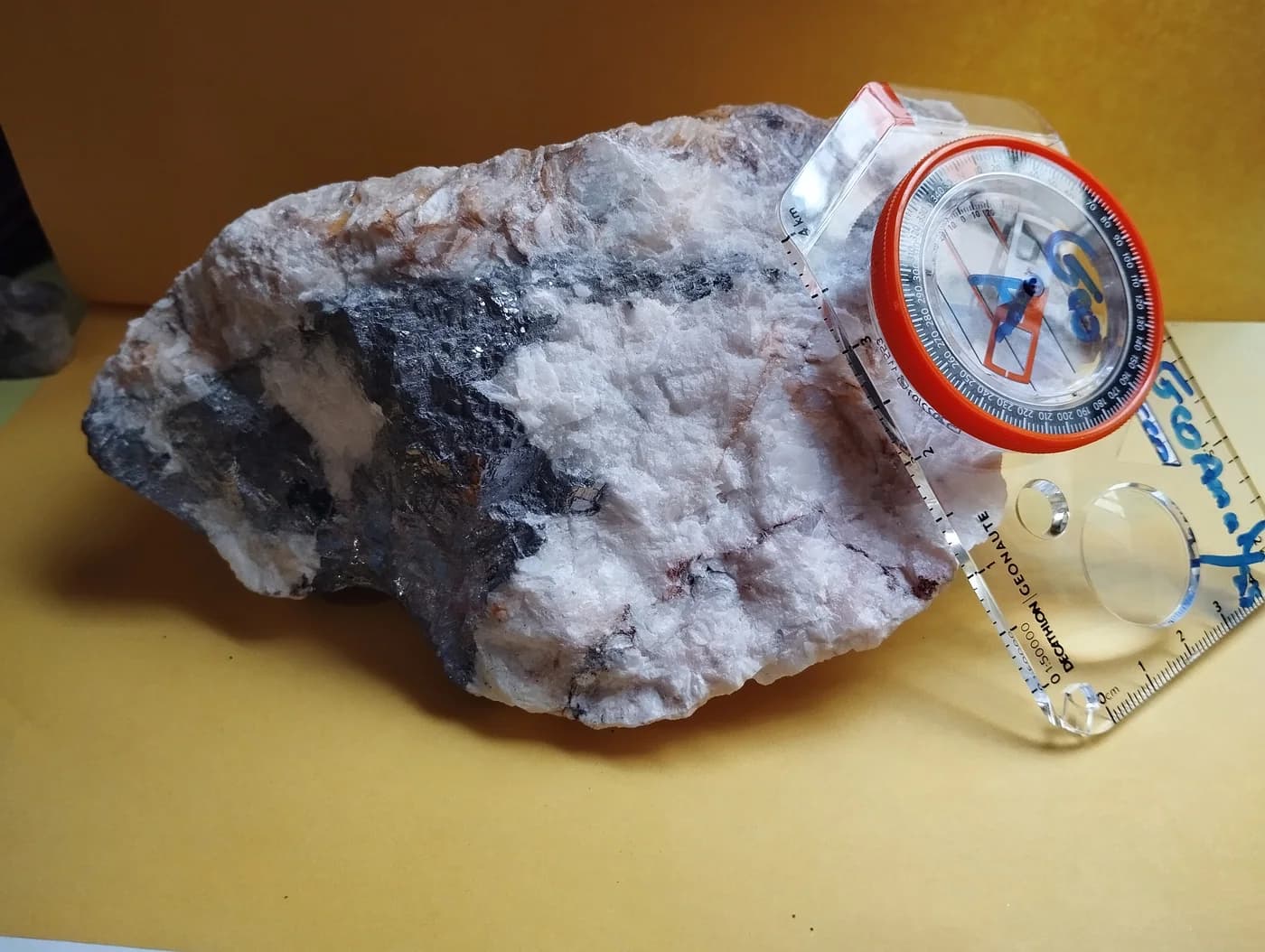Échantillon de roche accompagné d’une boussole et d’une échelle de terrain.